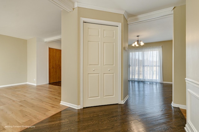 interior space featuring a notable chandelier, crown molding, baseboards, and wood finished floors