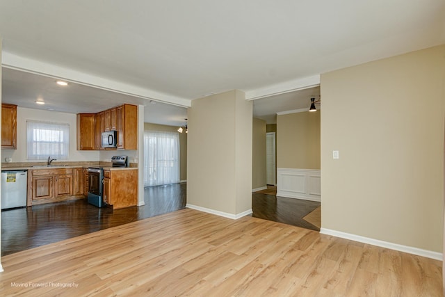 kitchen with a sink, stainless steel appliances, brown cabinetry, and dark wood-style flooring