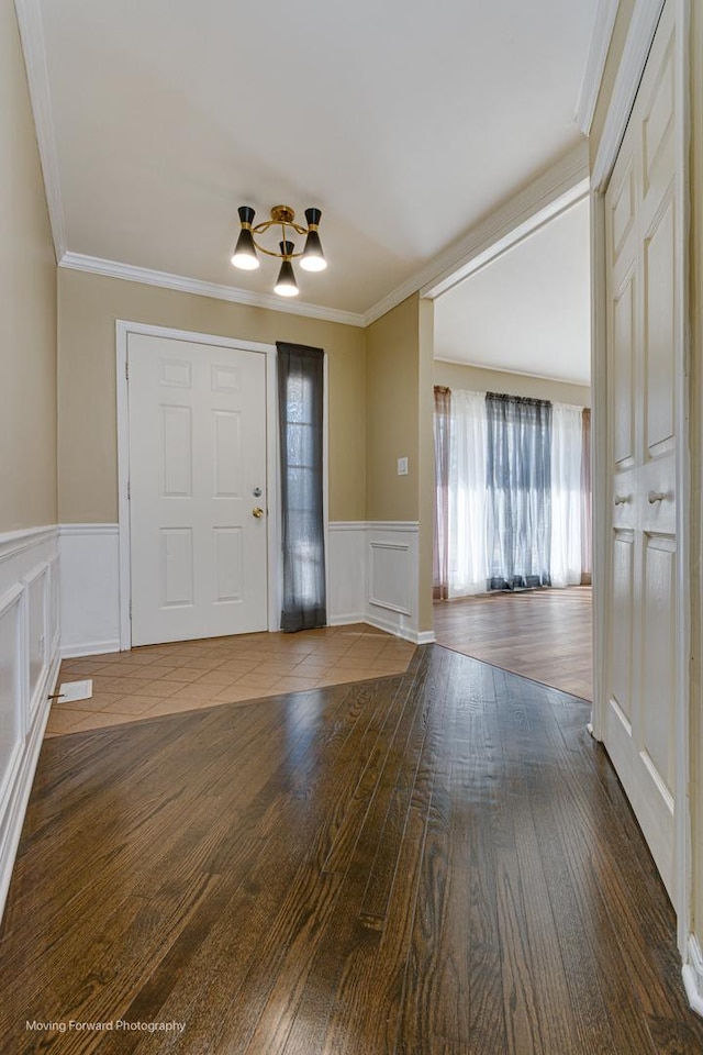 foyer with a wainscoted wall, wood finished floors, and crown molding