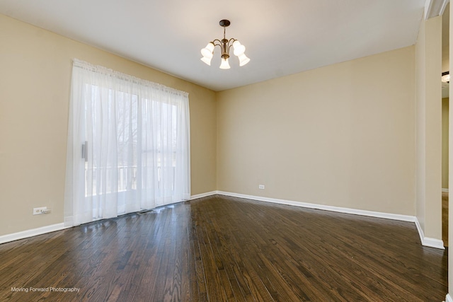 spare room featuring baseboards, dark wood-type flooring, and an inviting chandelier