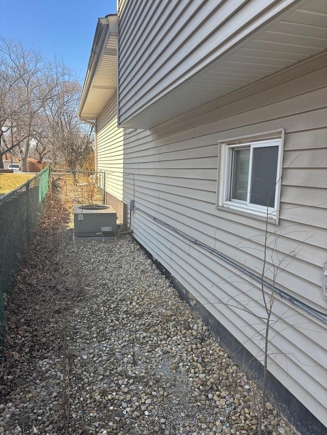 view of side of property with central AC unit and fence