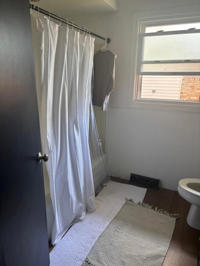 bathroom featuring toilet, a shower with curtain, wood finished floors, and visible vents