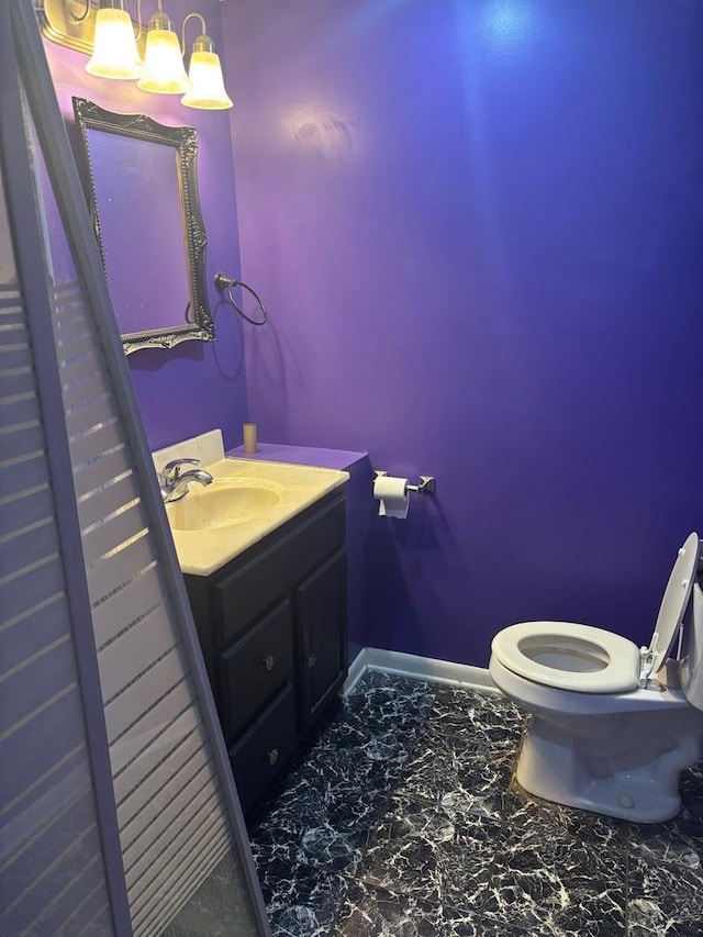 half bathroom with baseboards, toilet, marble finish floor, and vanity