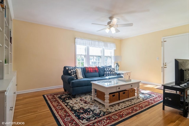 living room with baseboards, ornamental molding, a ceiling fan, and light wood finished floors