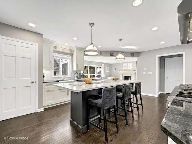 kitchen featuring a kitchen breakfast bar, dark wood-style floors, a center island, and white cabinetry