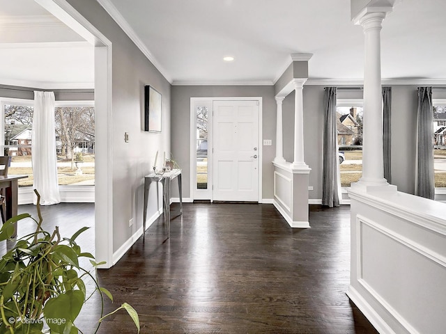 foyer with dark wood-style flooring, crown molding, baseboards, and decorative columns