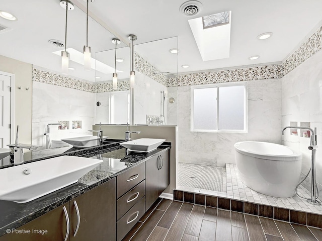 bathroom with a sink, visible vents, a skylight, and a walk in shower