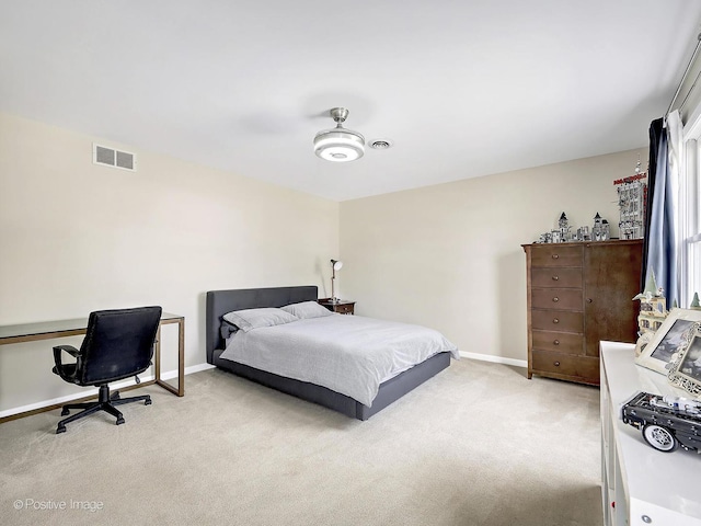 bedroom featuring visible vents, light colored carpet, and baseboards