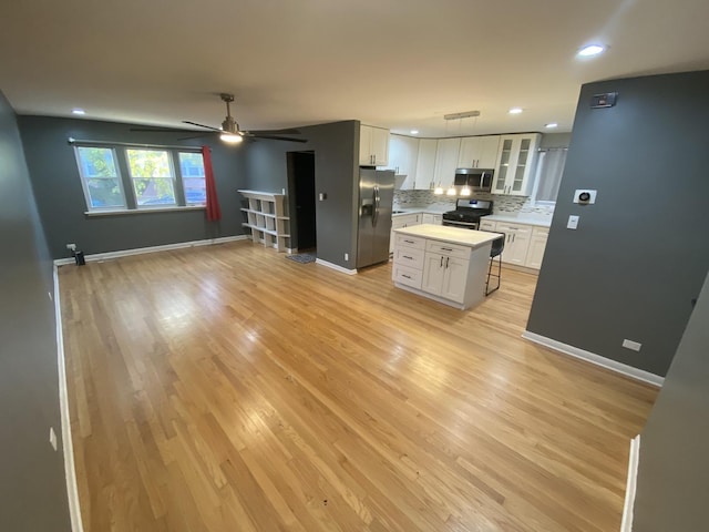 kitchen featuring light wood-style flooring, stainless steel appliances, decorative backsplash, light countertops, and white cabinetry