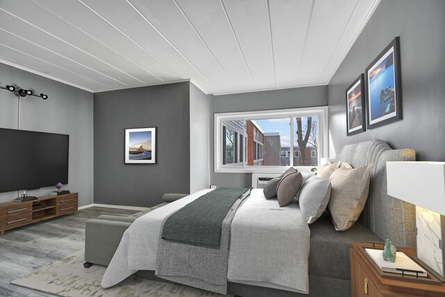 bedroom featuring baseboards, wood finished floors, and crown molding