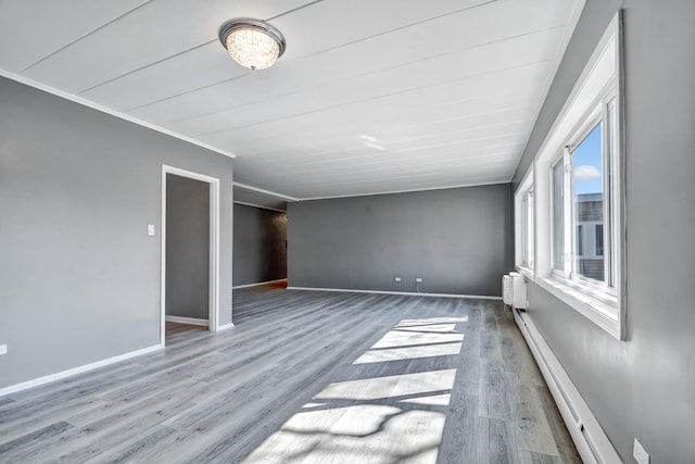 unfurnished room featuring a baseboard radiator, crown molding, baseboards, and wood finished floors