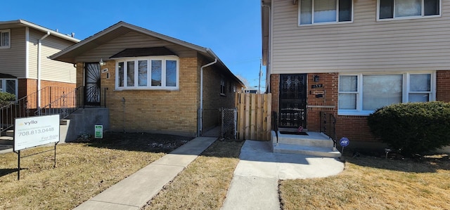 view of front of property with a gate, fence, and brick siding