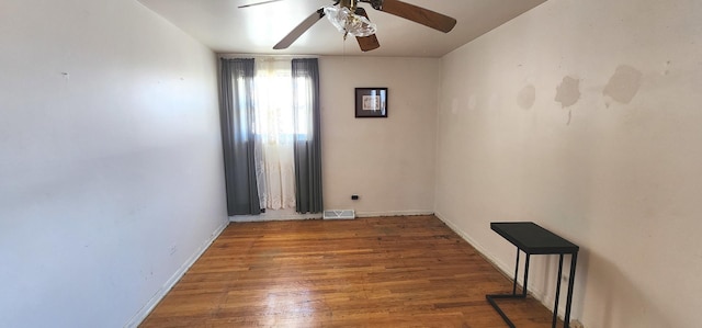 spare room with baseboards, wood finished floors, visible vents, and ceiling fan