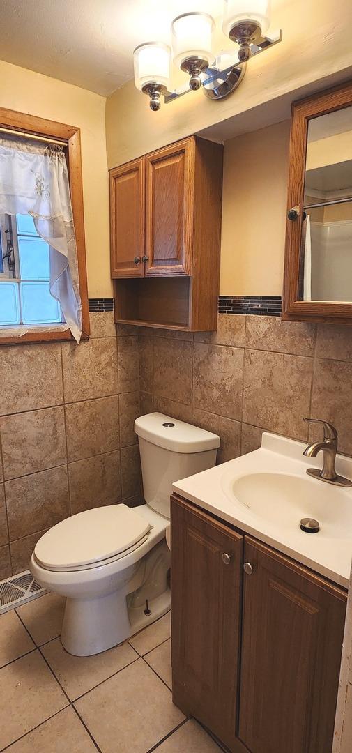 bathroom with vanity, visible vents, tile patterned flooring, tile walls, and toilet