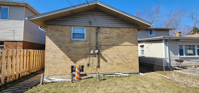 view of side of property featuring a yard, brick siding, and fence