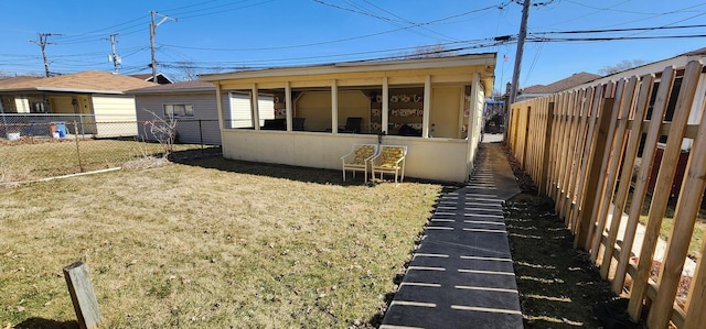 back of property featuring a yard, a fenced backyard, and a sunroom