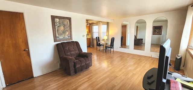 living area with arched walkways and light wood-style flooring