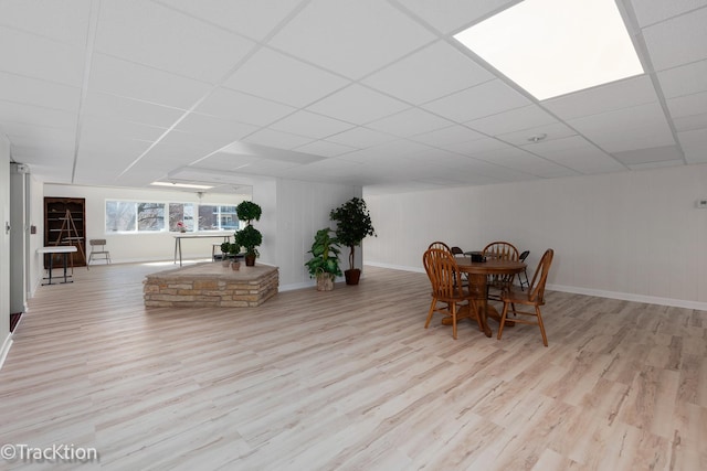 dining room featuring a drop ceiling, baseboards, and wood finished floors