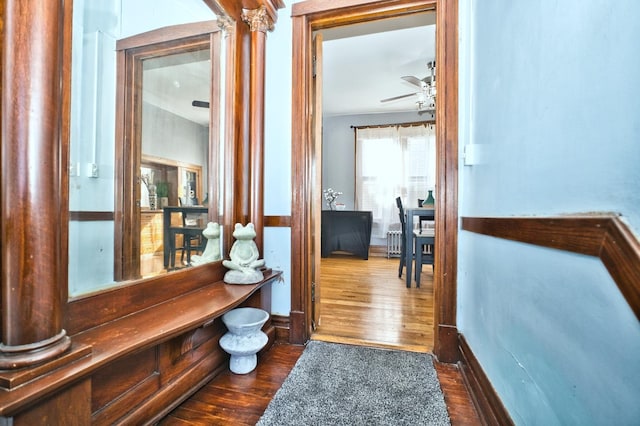 hallway with ornate columns and dark wood-style flooring