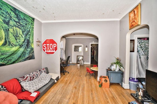 interior space featuring hardwood / wood-style floors, baseboards, arched walkways, and ornamental molding