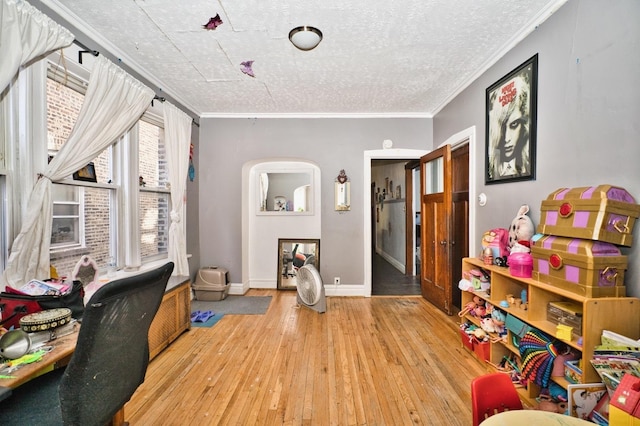 office area featuring crown molding, baseboards, hardwood / wood-style flooring, arched walkways, and a textured ceiling