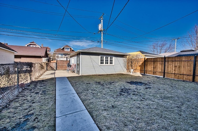 view of yard featuring an outdoor structure, a fenced backyard, and a gate