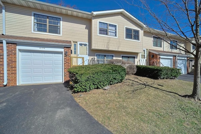 view of front of house with aphalt driveway, an attached garage, and brick siding