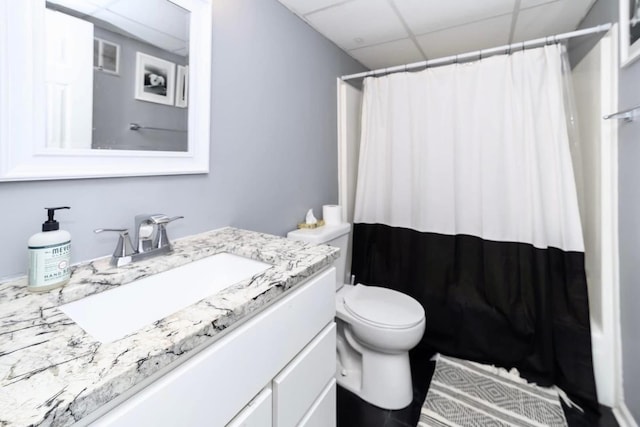 full bath featuring a shower with shower curtain, a paneled ceiling, toilet, and vanity