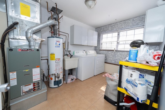 washroom featuring washer and dryer, heating unit, water heater, cabinet space, and light tile patterned flooring