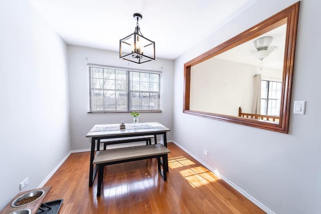 dining area with a chandelier, plenty of natural light, baseboards, and wood-type flooring