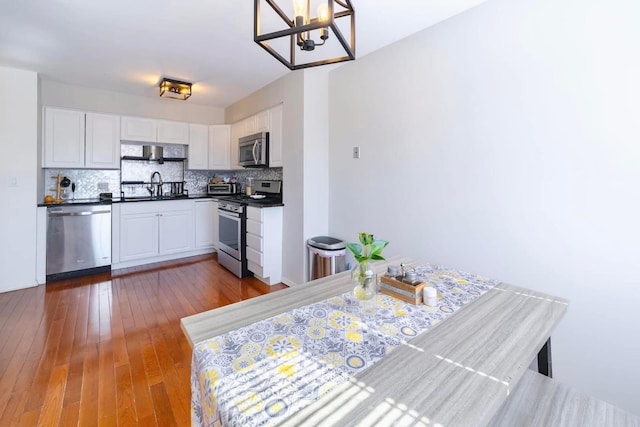 kitchen with dark countertops, backsplash, appliances with stainless steel finishes, and a sink