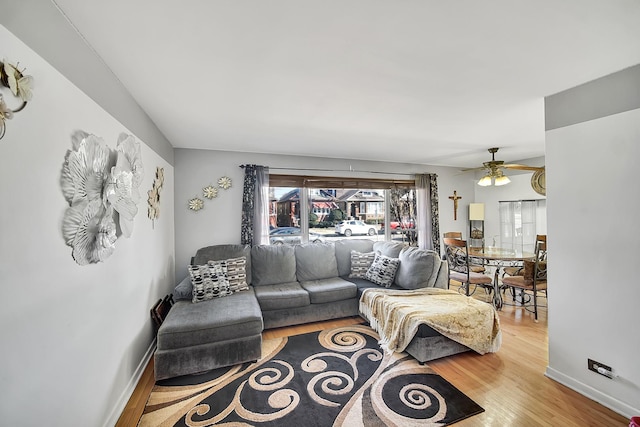 living area featuring baseboards, wood finished floors, and a ceiling fan