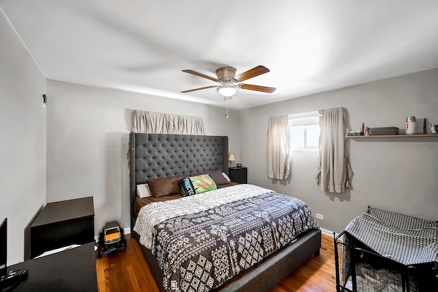 bedroom featuring baseboards, wood finished floors, and a ceiling fan