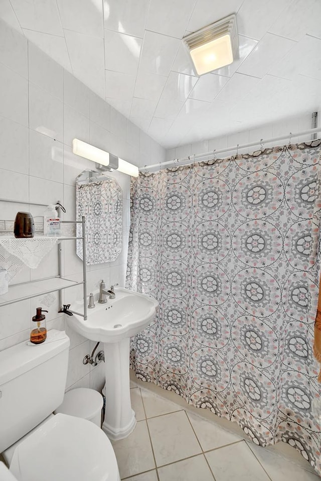 full bathroom featuring curtained shower, toilet, tile walls, and tile patterned flooring