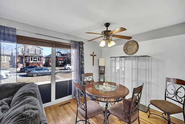 dining area featuring visible vents, ceiling fan, and light wood finished floors