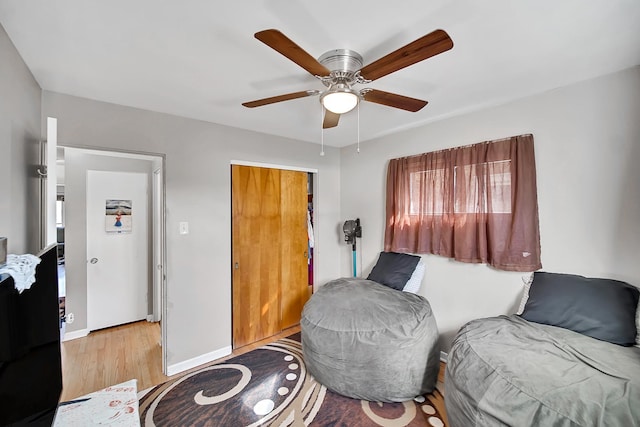 living area with ceiling fan, baseboards, and wood finished floors