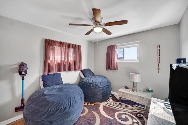 living area featuring baseboards and ceiling fan