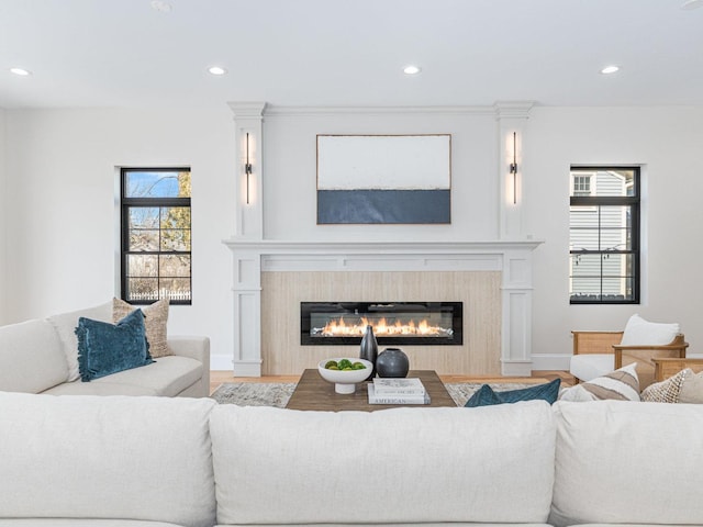 living room featuring a glass covered fireplace, recessed lighting, and wood finished floors