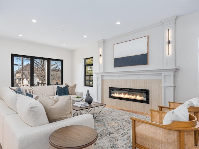 living area featuring a glass covered fireplace, wood finished floors, and recessed lighting