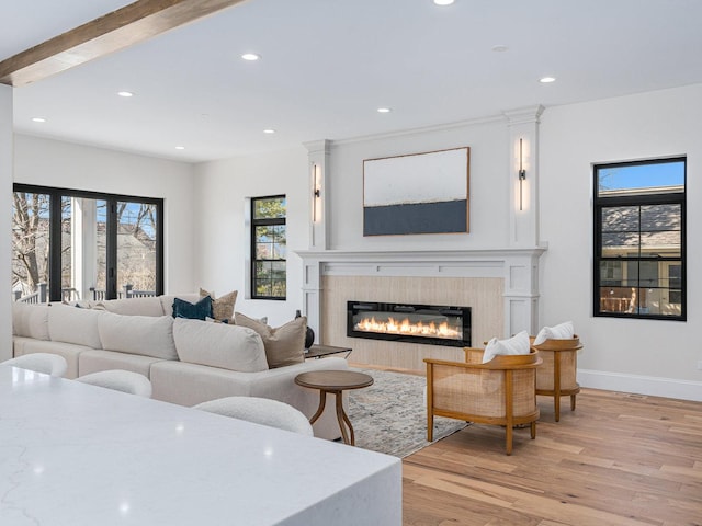 living room with a glass covered fireplace, baseboards, light wood-style flooring, and recessed lighting