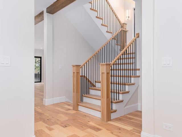 staircase with beamed ceiling, wood finished floors, baseboards, and high vaulted ceiling