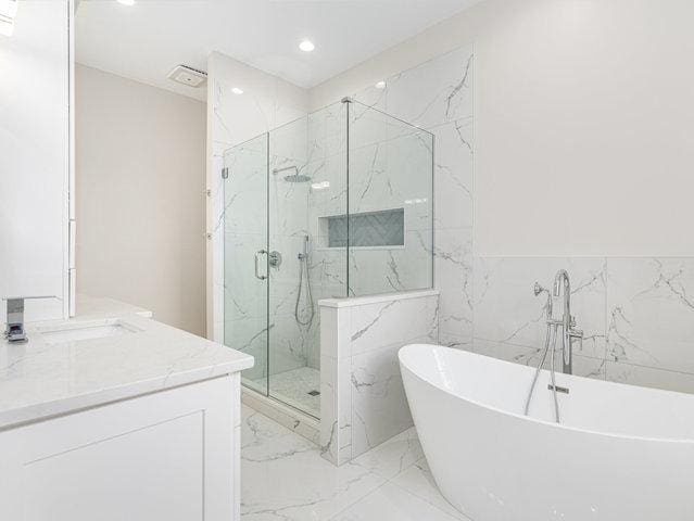 bathroom with a freestanding tub, marble finish floor, recessed lighting, a marble finish shower, and vanity