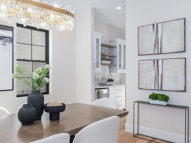 dining area featuring light wood-style flooring, recessed lighting, wine cooler, bar, and a chandelier