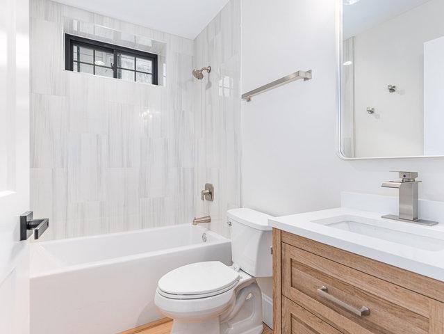 bathroom with vanity,  shower combination, and toilet