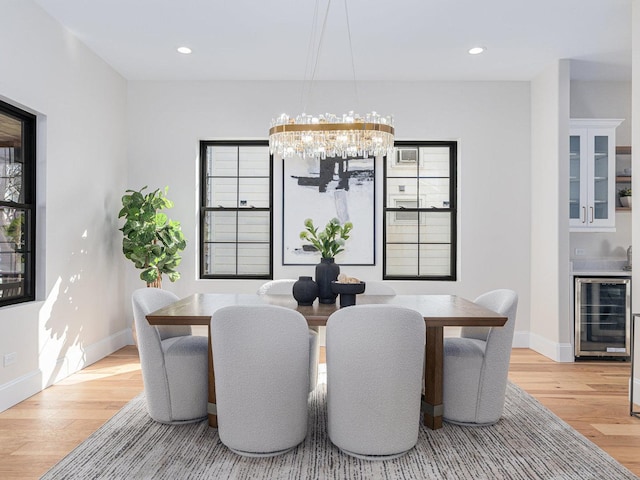 dining space with light wood finished floors, baseboards, wine cooler, recessed lighting, and a notable chandelier