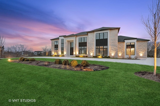 contemporary house featuring a yard, stone siding, and stucco siding