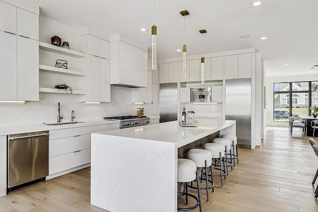 kitchen featuring a sink, a breakfast bar, white cabinets, stainless steel appliances, and modern cabinets