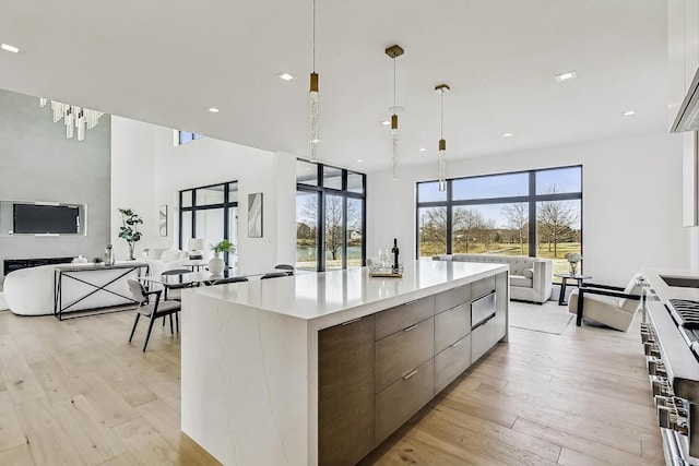 kitchen featuring hanging light fixtures, light countertops, light wood-style floors, modern cabinets, and open floor plan