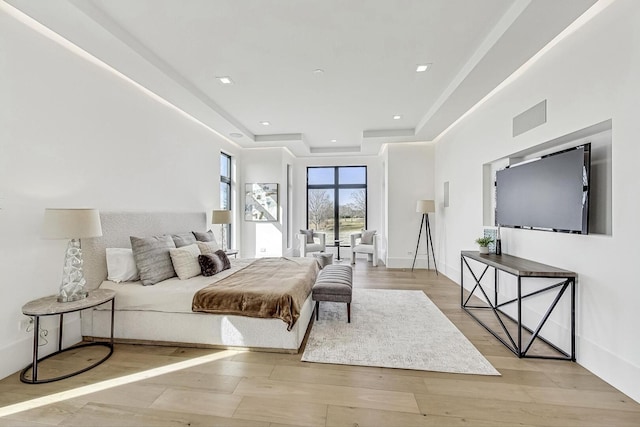 bedroom featuring recessed lighting, a tray ceiling, baseboards, and wood finished floors