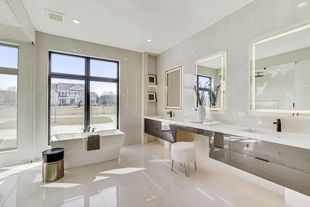 full bath featuring double vanity, a soaking tub, tile patterned flooring, and a sink